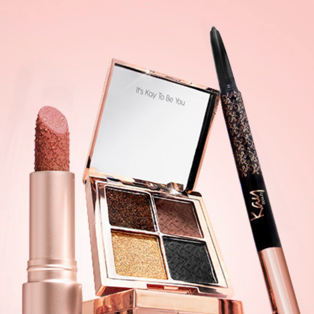 Collection of Kay Beauty buys on a pink background, including a lipstick, eyeshadow and eyeliner