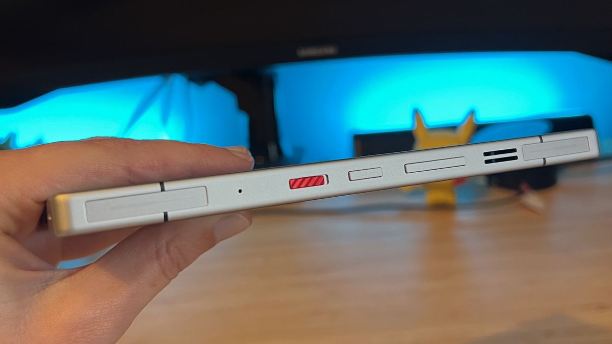 Hand holding RedMagic 11 Pro on its side with touch triggers and controls visible