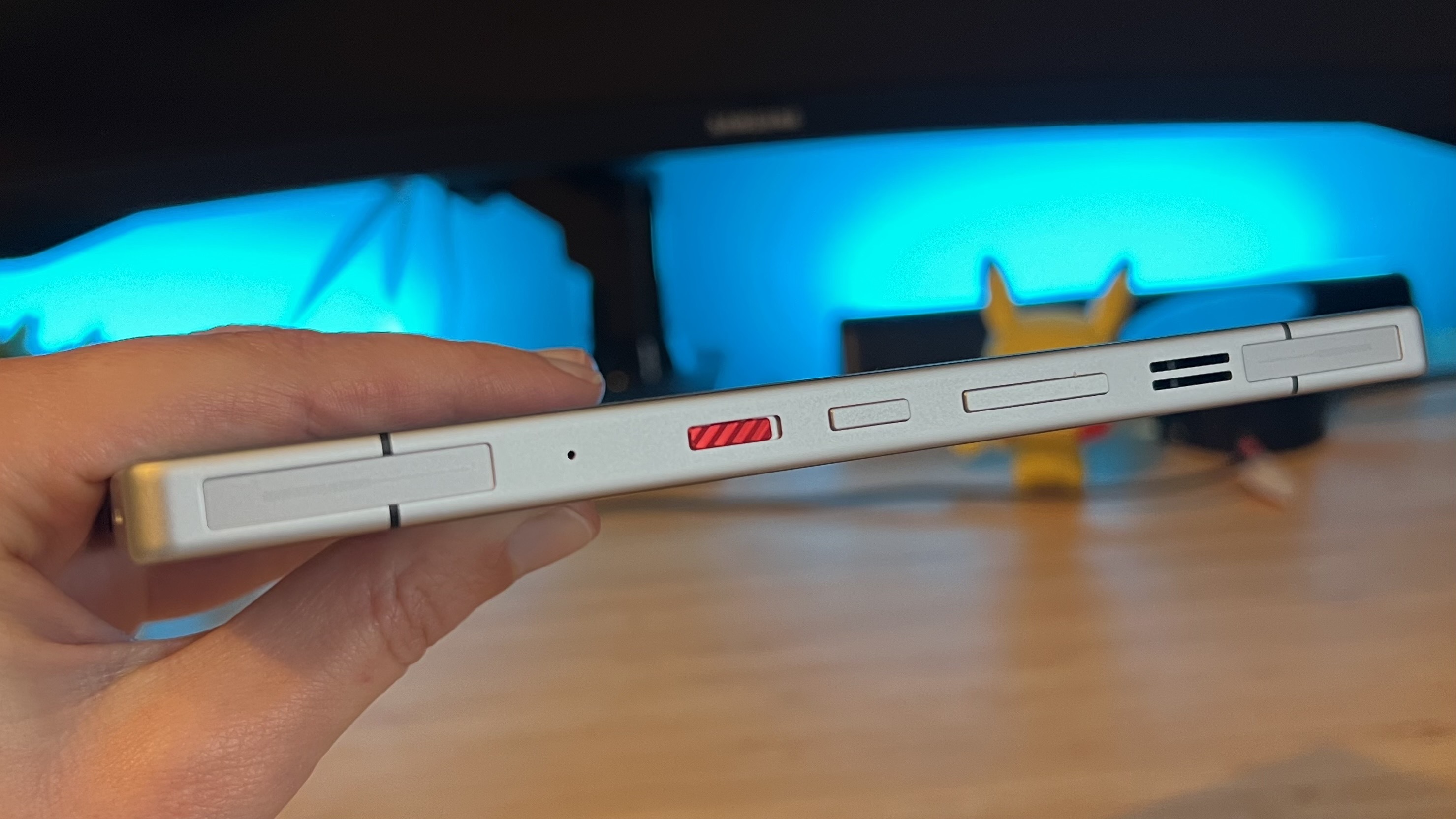 Hand holding RedMagic 11 Pro on its side with touch triggers and controls visible