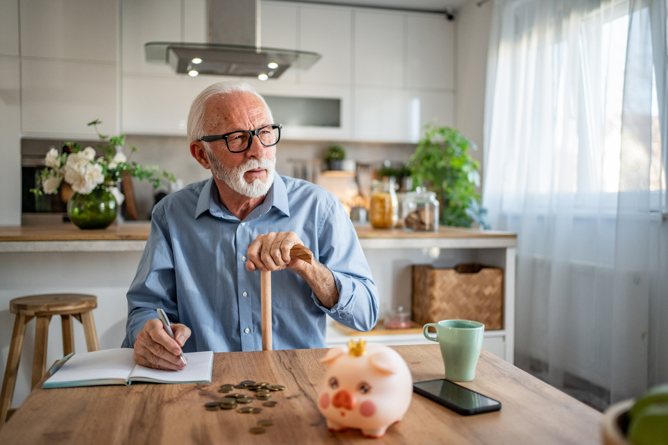 Older man looking at his pension savings with a piggy bank on the table