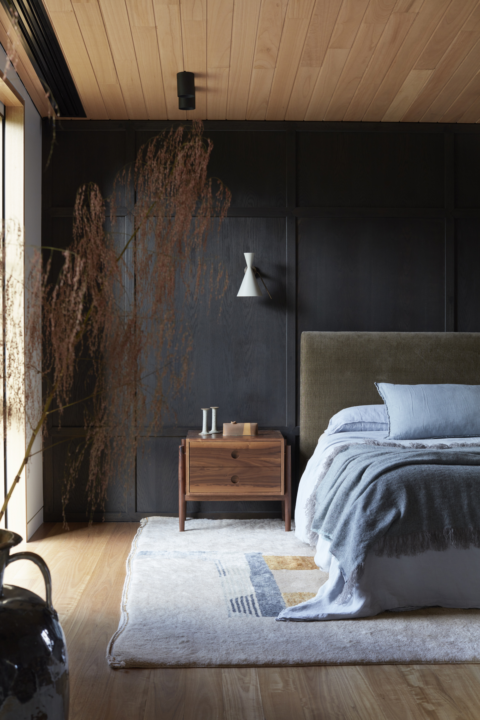 black wood walls with light wood ceiling and floor, green headboard