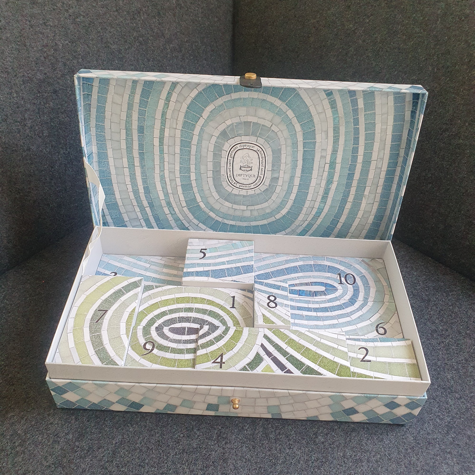 Open Diptyque Summer Essentials calendar on a dark grey sofa