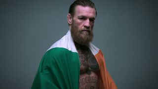 Conor McGregor poses for a photograph with an Irish flag draped on his shoulders