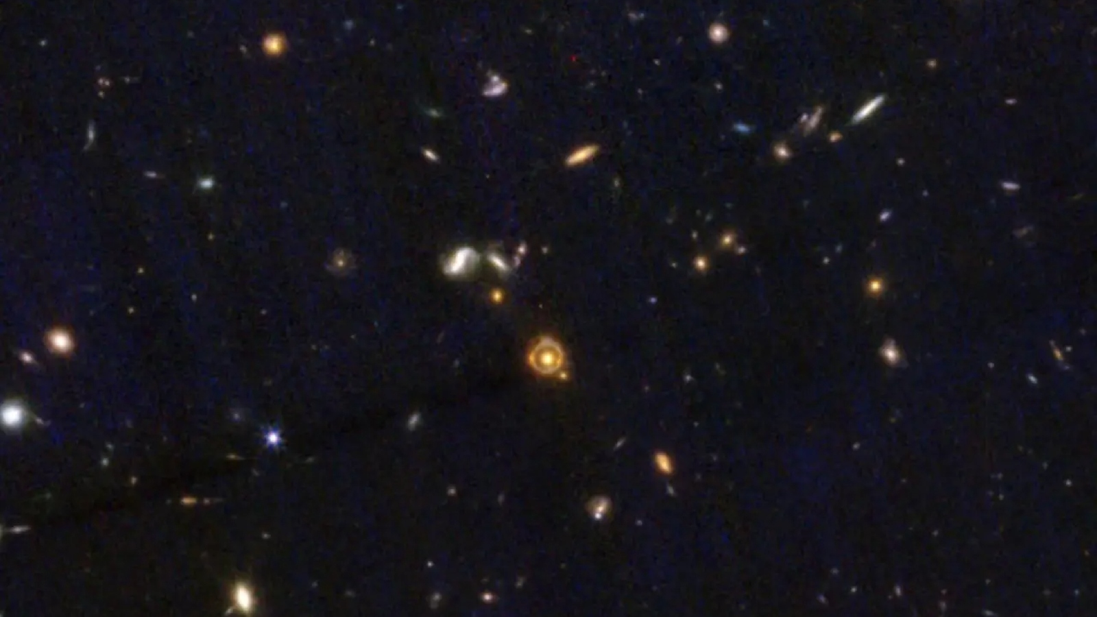 A deep field view of space with a tiny Einstein ring in the middle
