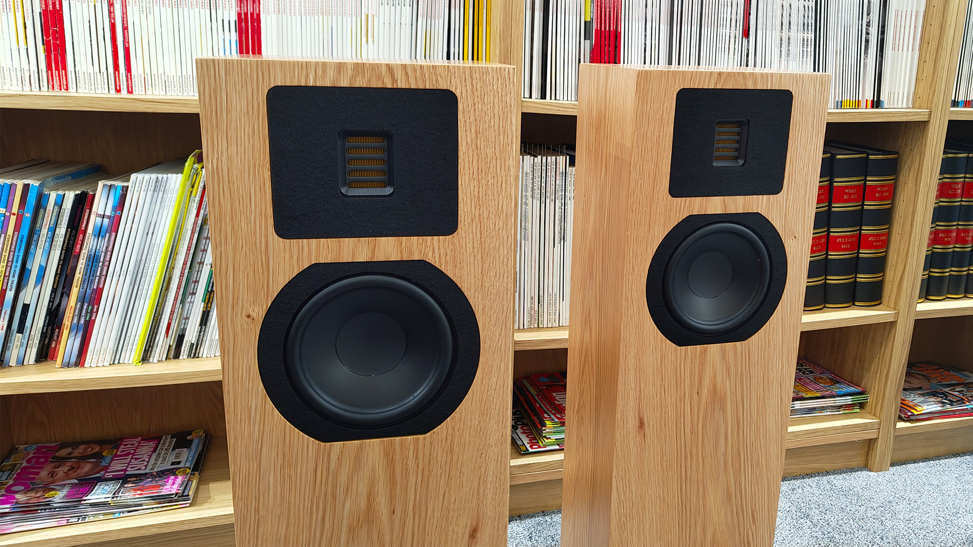 Neat Mystique Classic floorstanding speakers on grey carpet in front of bookcase, focus on drive units