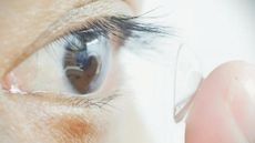 A study participant places one of the night vision lenses in their eye.