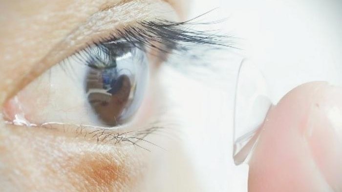 A study participant places one of the night vision lenses in their eye.