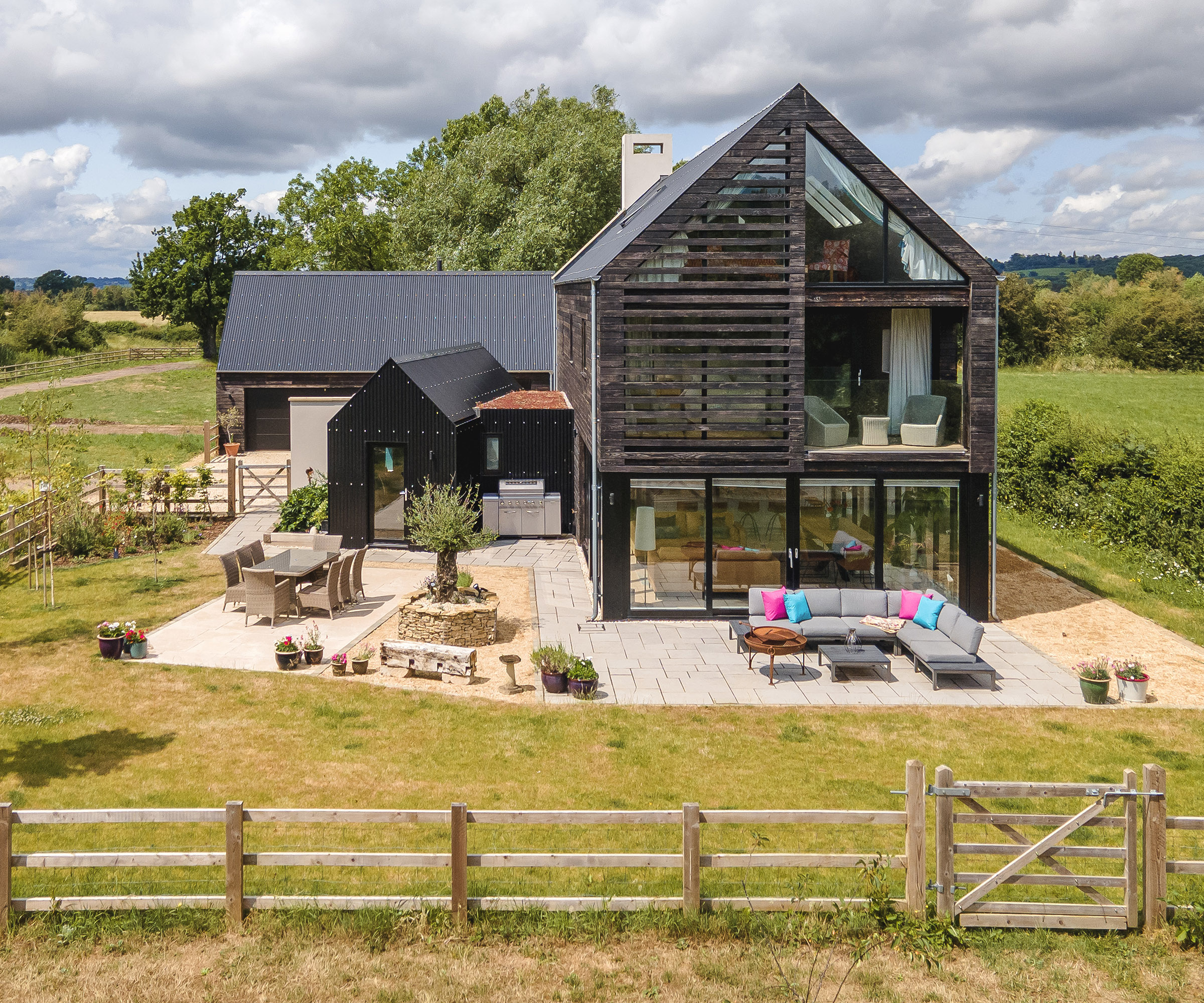 A three storey self build home clad in shou sugi ban timber with a spacious patio with sliding doors