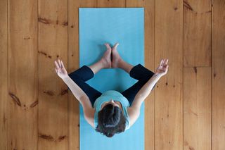 Overhead shot of a pregnant woman doing yoga on a blue yoga mat