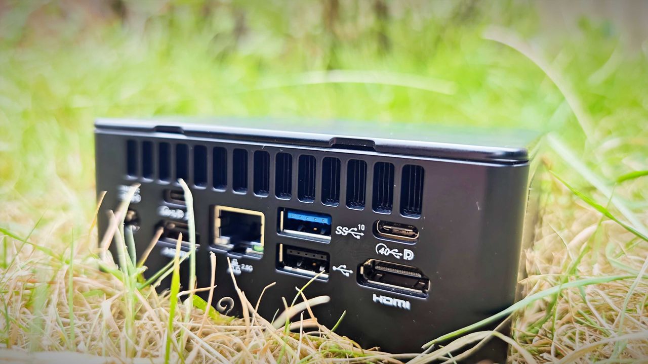A black Geekom IT15 mini PC sitting in a grassy field