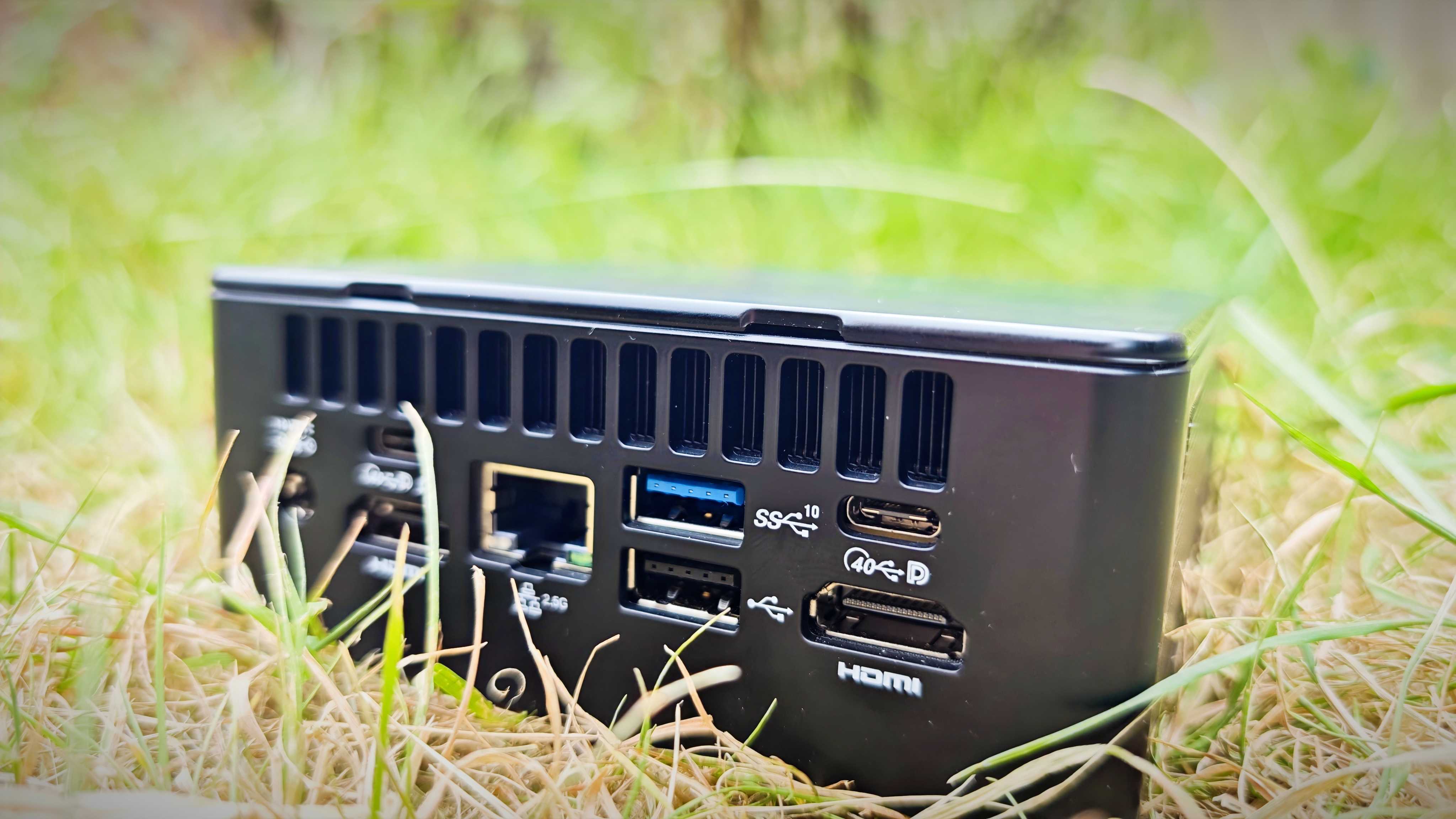 A black Geekom IT15 mini PC sitting in a grassy field