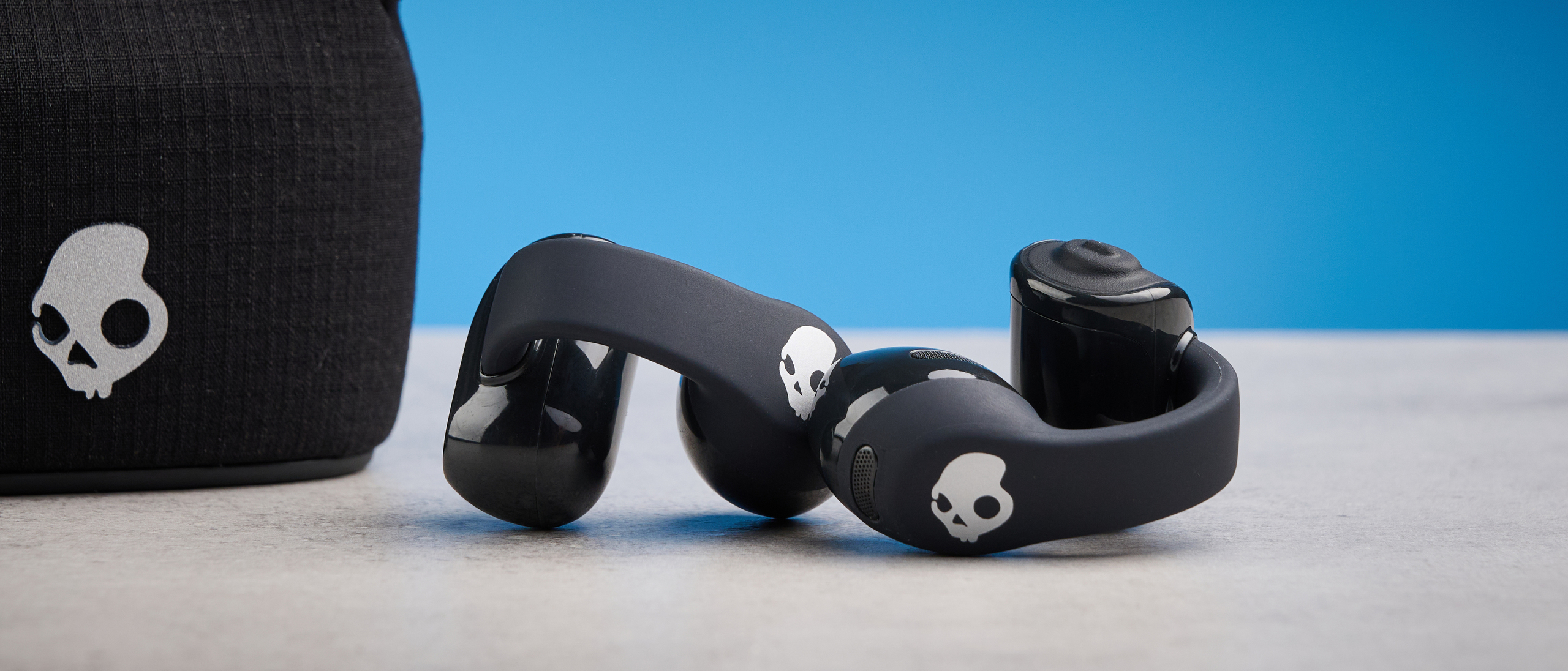 Skullcandy Push 720 Open in black and silver colorway with charging case photographed on a blue background