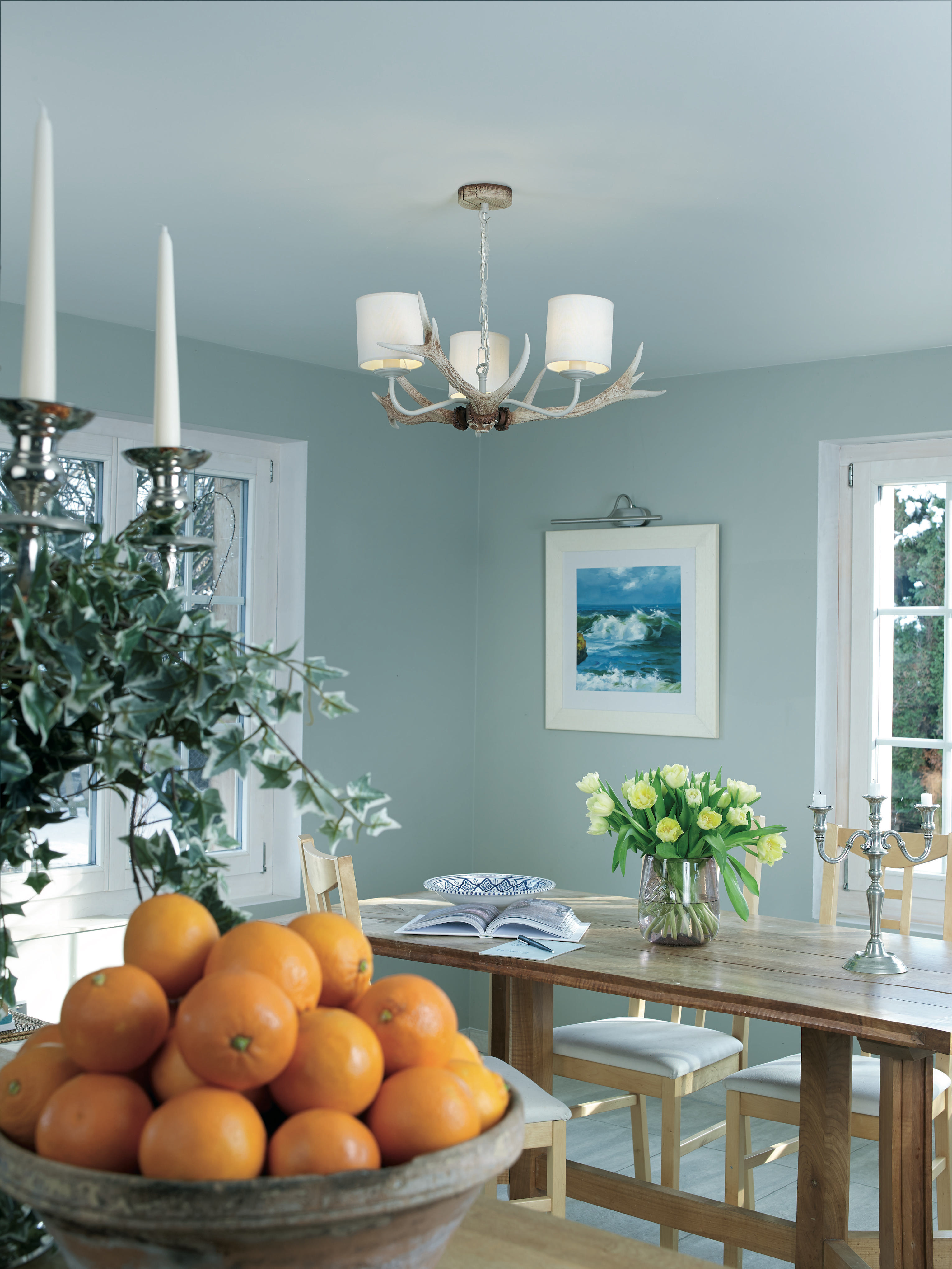 blue dining room with rustic elements, wooden dining table and antler pendant light