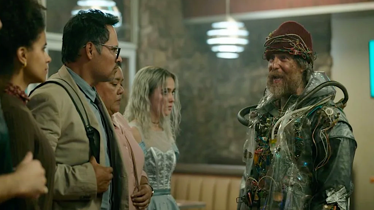 رجل أشعث يرتدي زيًا من القمامة والأسلاك يتحدث إلى الناس في المطعم