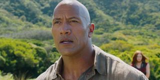 Dr. Xander Bravestone (Dwayne Johnson) stands in front of a lush jungle in 'Jumanji: Welcome to the Jungle'