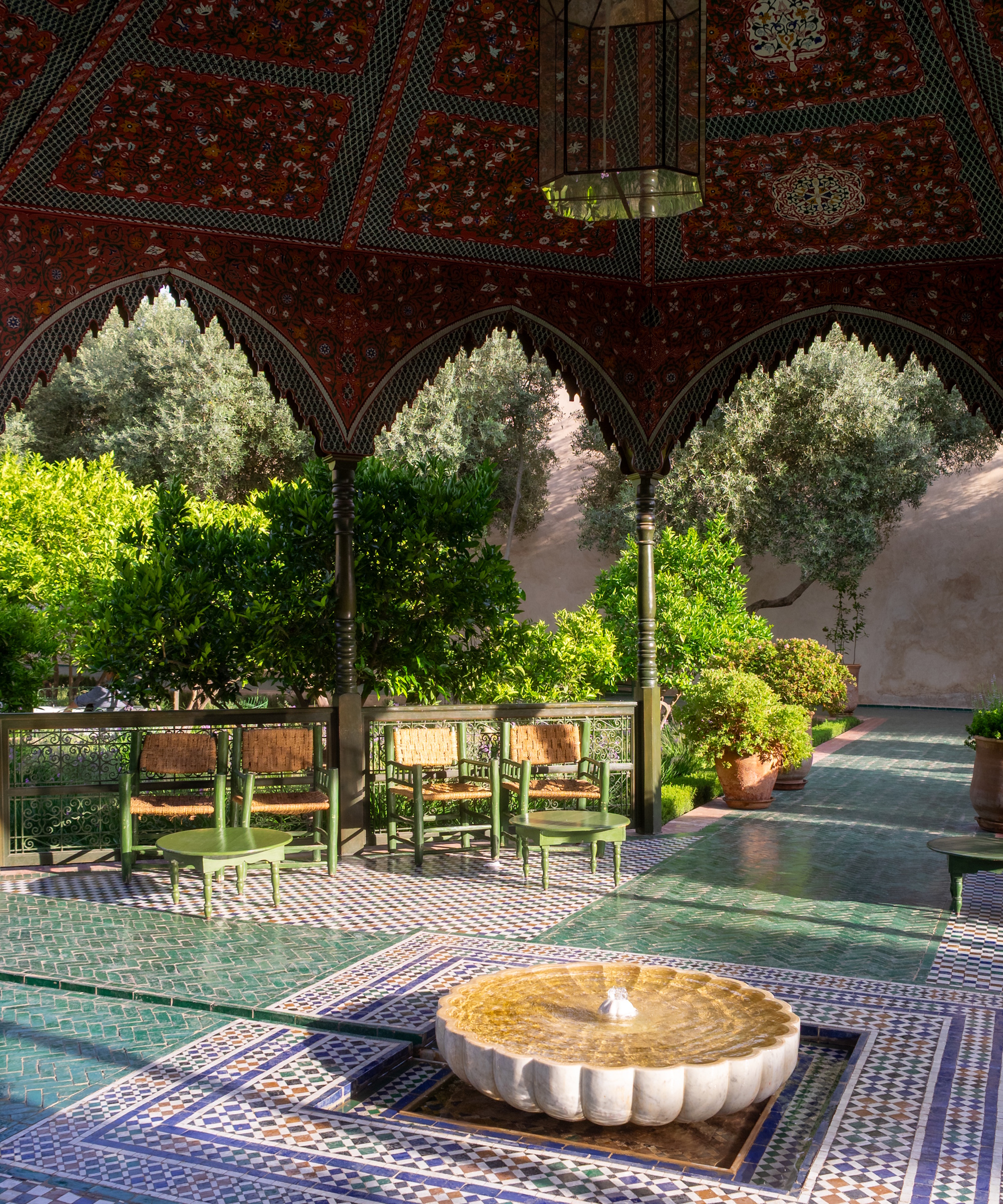 Moroccan courtyard with scalloped bubbling fountain and green table and chairs