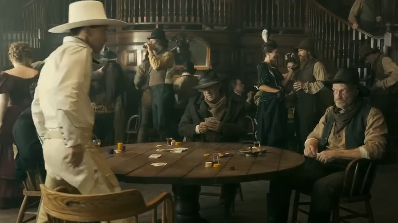Tim Black Nelson in all white sitting down at a poker table in The Ballad Of Buster Scruggs