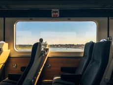 Side view of empty passenger seats in a modern train carriage interior with scenic coastal view out of the window at dusk