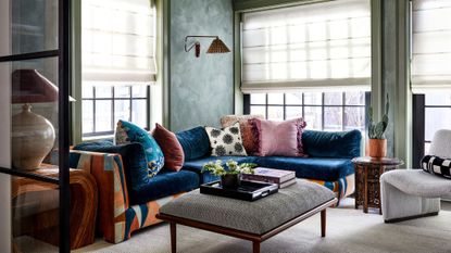 living room with green plaster walls and blue sofa with colorful cushions in front of windows