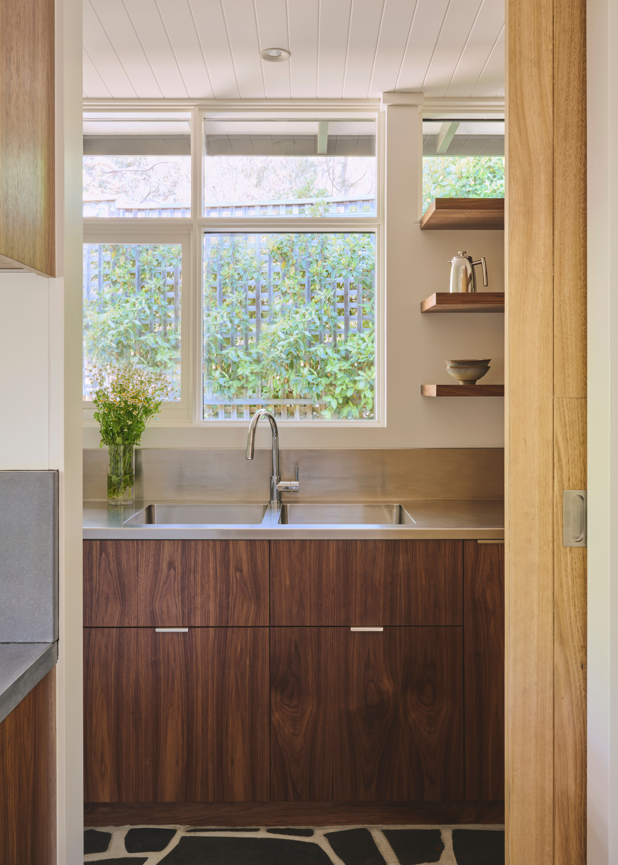 A small kitchen with windows and open shelving