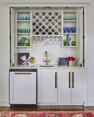 small home bar with white cabinets, folded doors, wine rack, shelving, sink, fridge, hardwood floor, rug