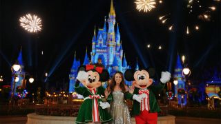 Lacey Chabert films outside of the castle at Disney World's Magic Kingdom with Mickey Mouse and Minnie Mouse in holiday gear. 