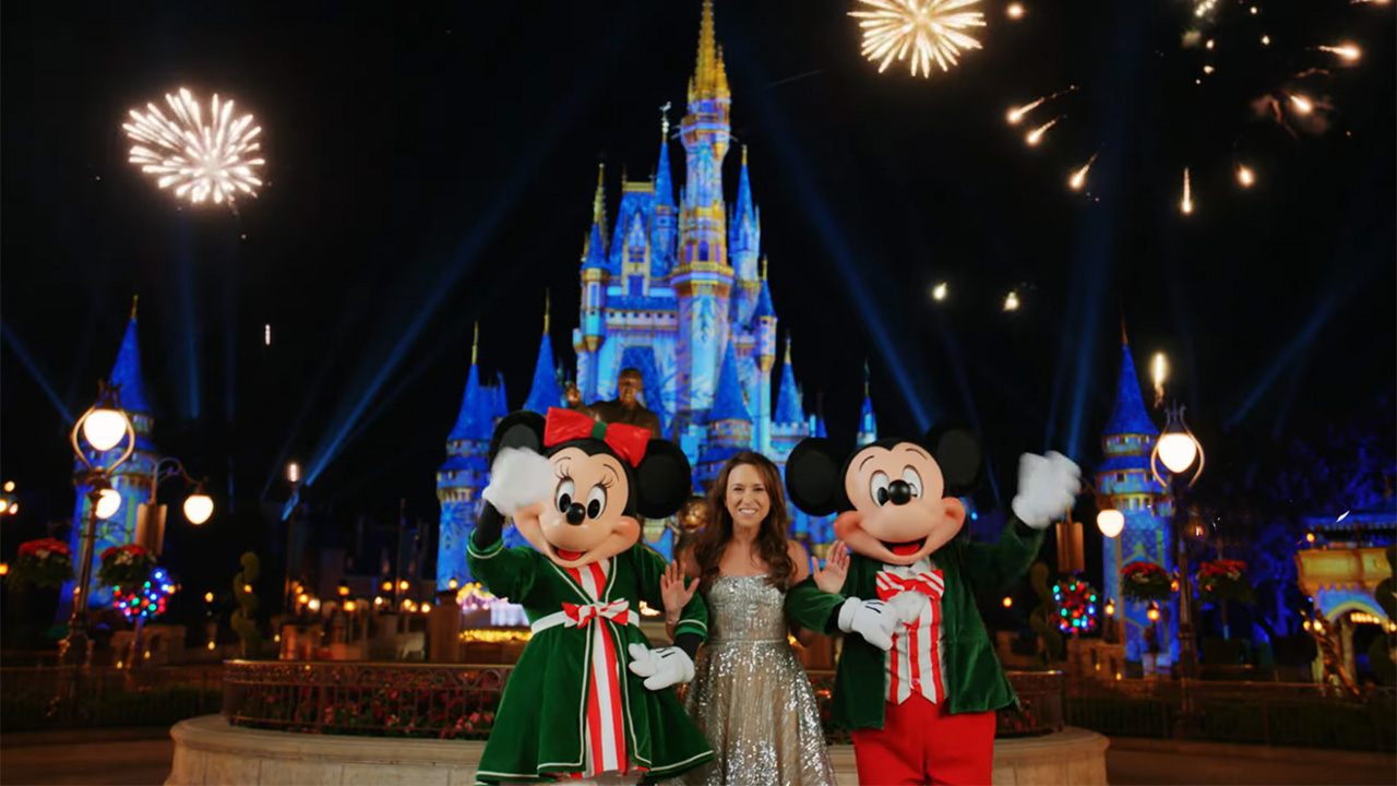 Lacey Chabert films outside of the castle at Disney World's Magic Kingdom with Mickey Mouse and Minnie Mouse in holiday gear. 