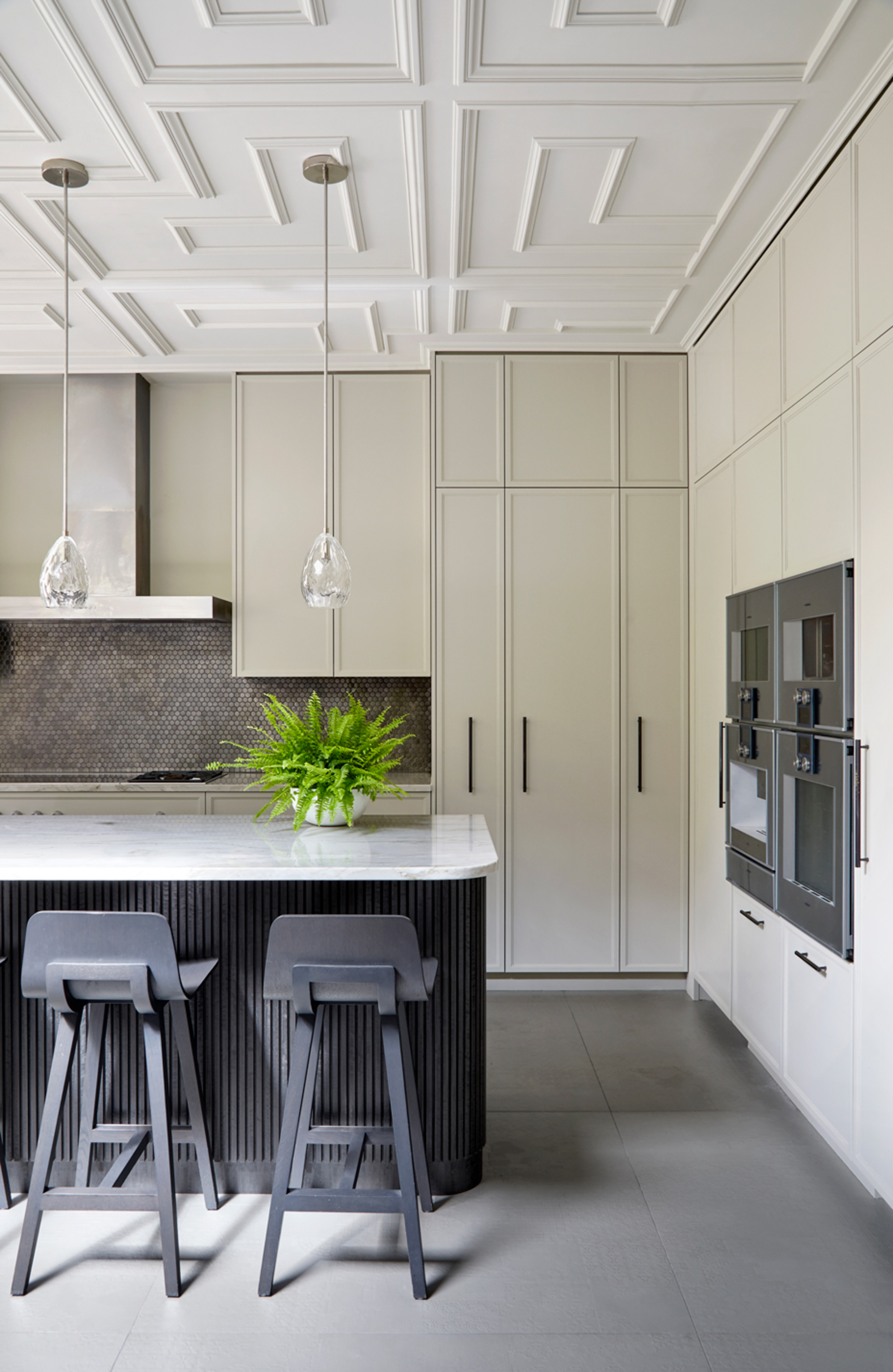 modern kitchen with decorative molding on ceiling, beige cabinetry, gray floor tiles, fluted kitchen island, gray backsplash tiles, and white marble countertop