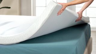 Woman lifting a mattress topper off bed