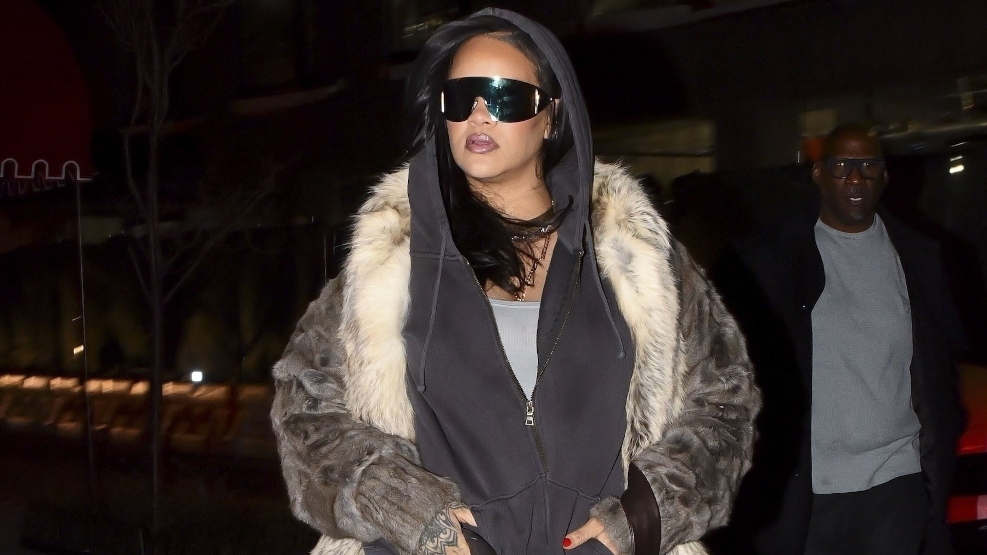 Rihanna layered an oversize hoodie underneath a Saint Laurent fur coat with flared jeans