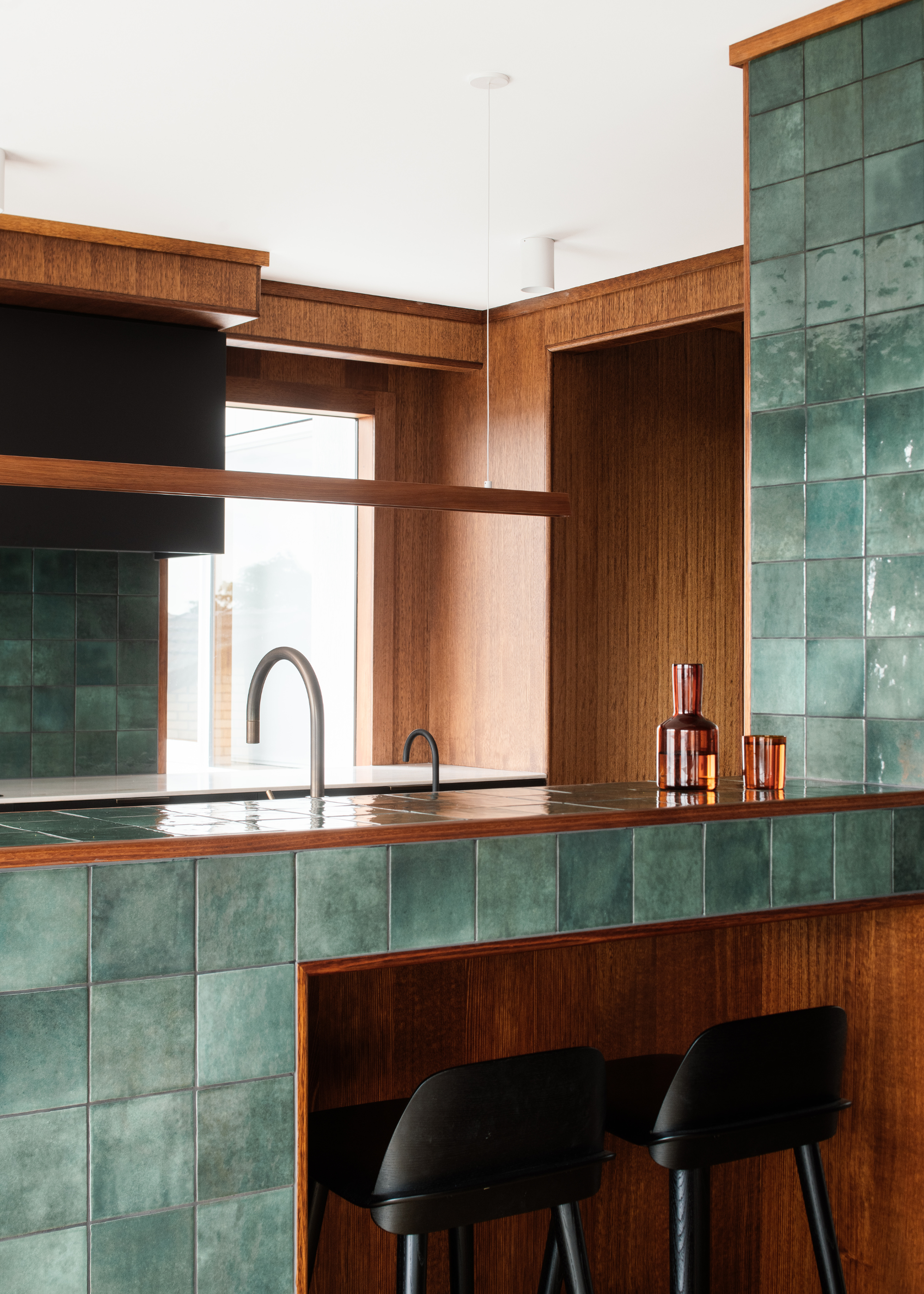 a 70s style home with lots of warm dark wood and green tiled kitchen