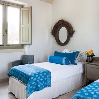 bedroom with white wall and bed with blue cushions