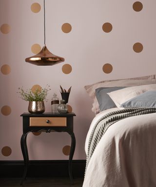 A teenage girl bedroom idea with pale pink walls, stencilled gold spot pattern and bronze pendant lamp