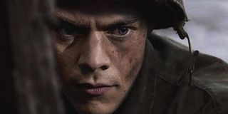 Dunkirk Harry Styles in uniform, wearing a helmet, grimacing in place
