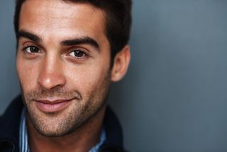 A man smiling on a blue background.