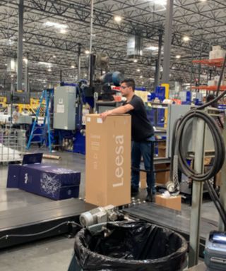 A man sealing a Leesa mattress box in the 3Z factory.