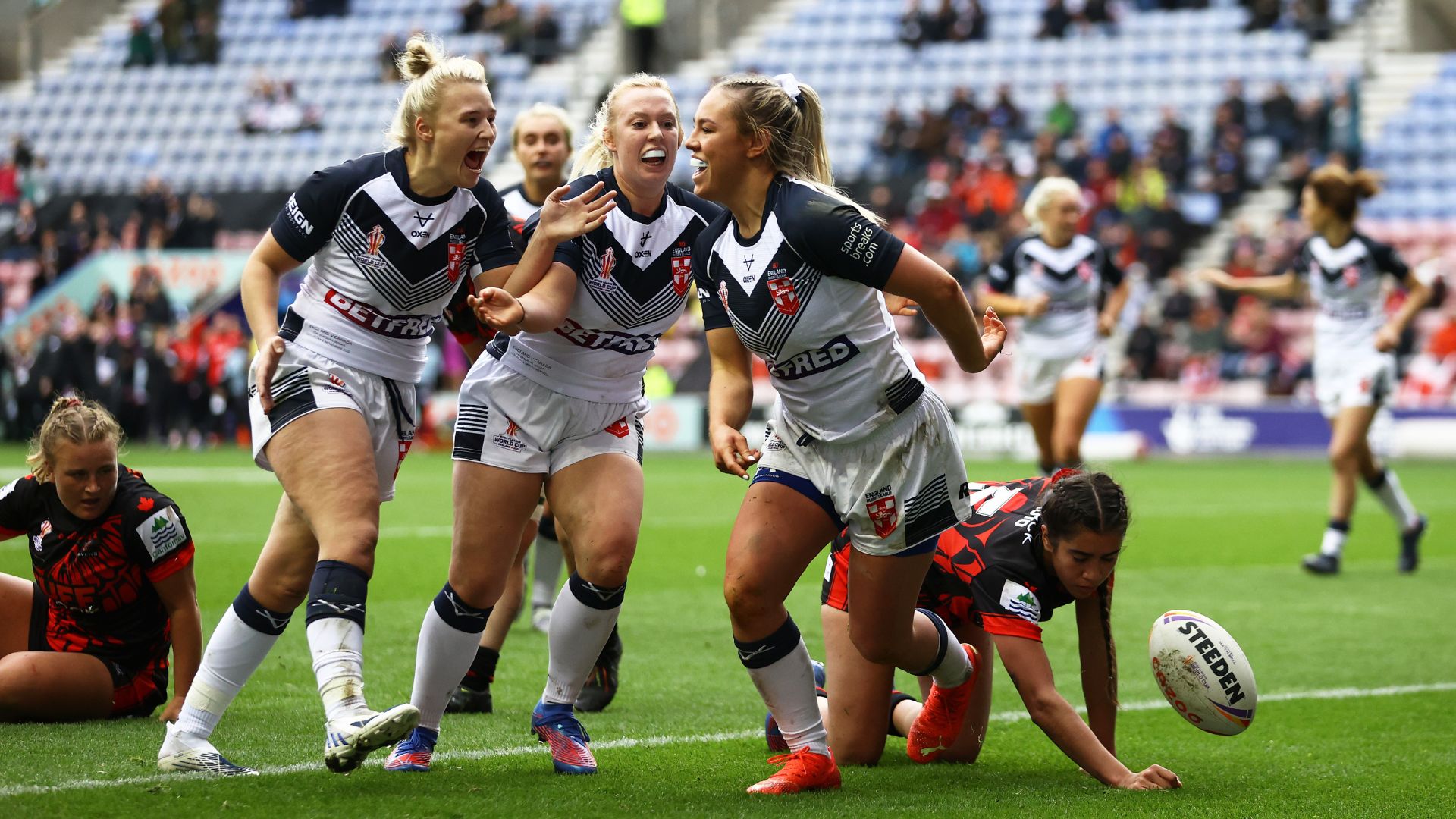 WIGAN, ENGLAND - NOVEMBER 05: Hollie Dodd of England celebrates their sides second try with team mates during the Women's Rugby League World Cup Group A match between England Women and Canada Women at DW Stadium on November 05, 2022 in Wigan, England.