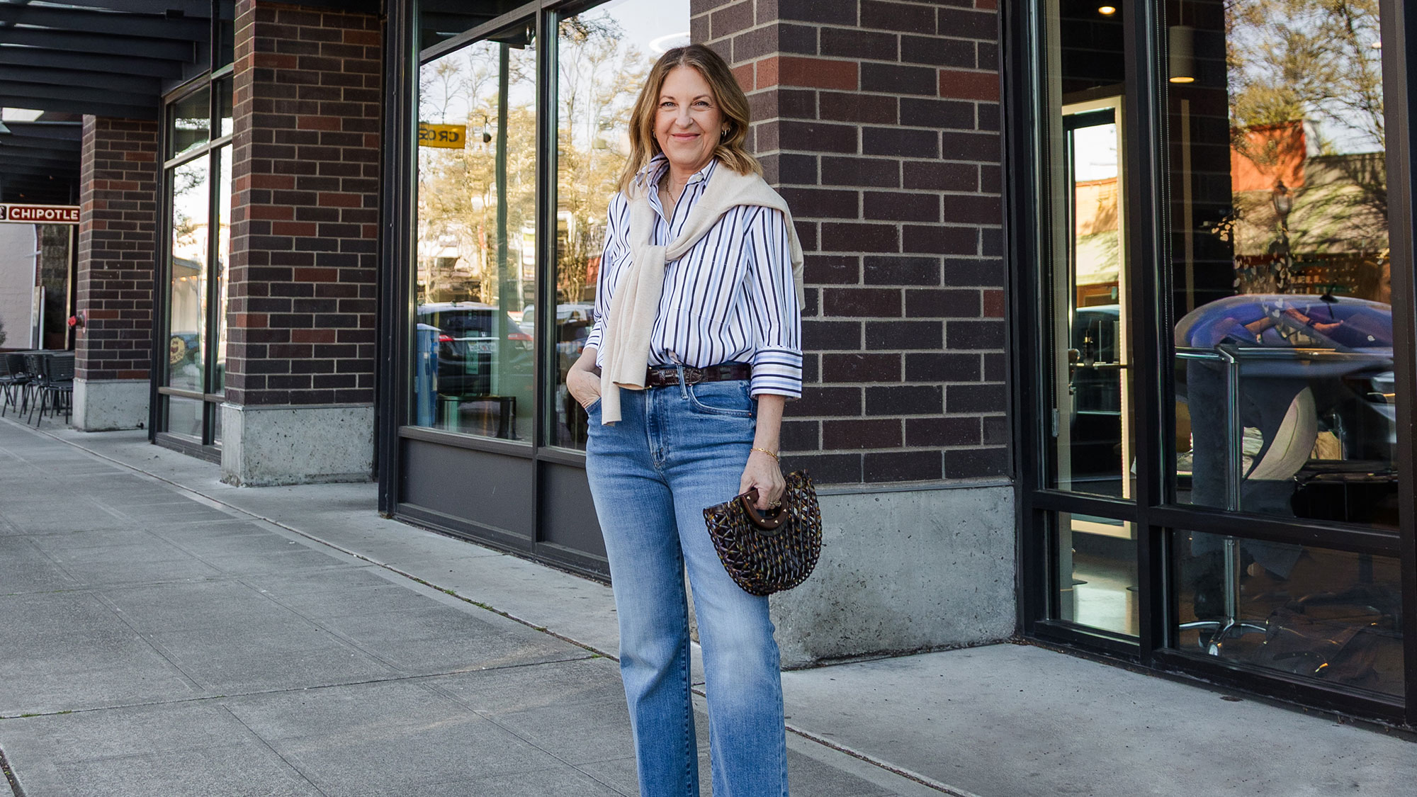 A former VIP Nordstrom stylist wearing a striped button-down and jeans.