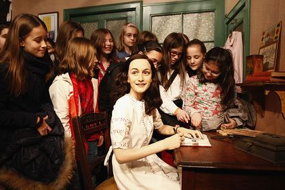 Girls surround a wax figure of Anne Frank