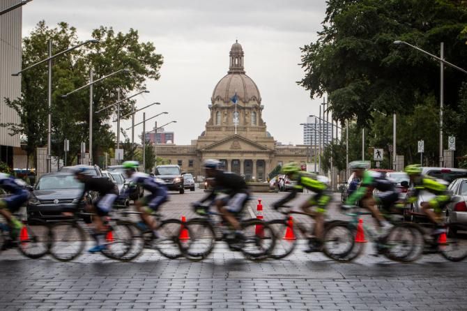Riders pass by the capitol building in Edmonton