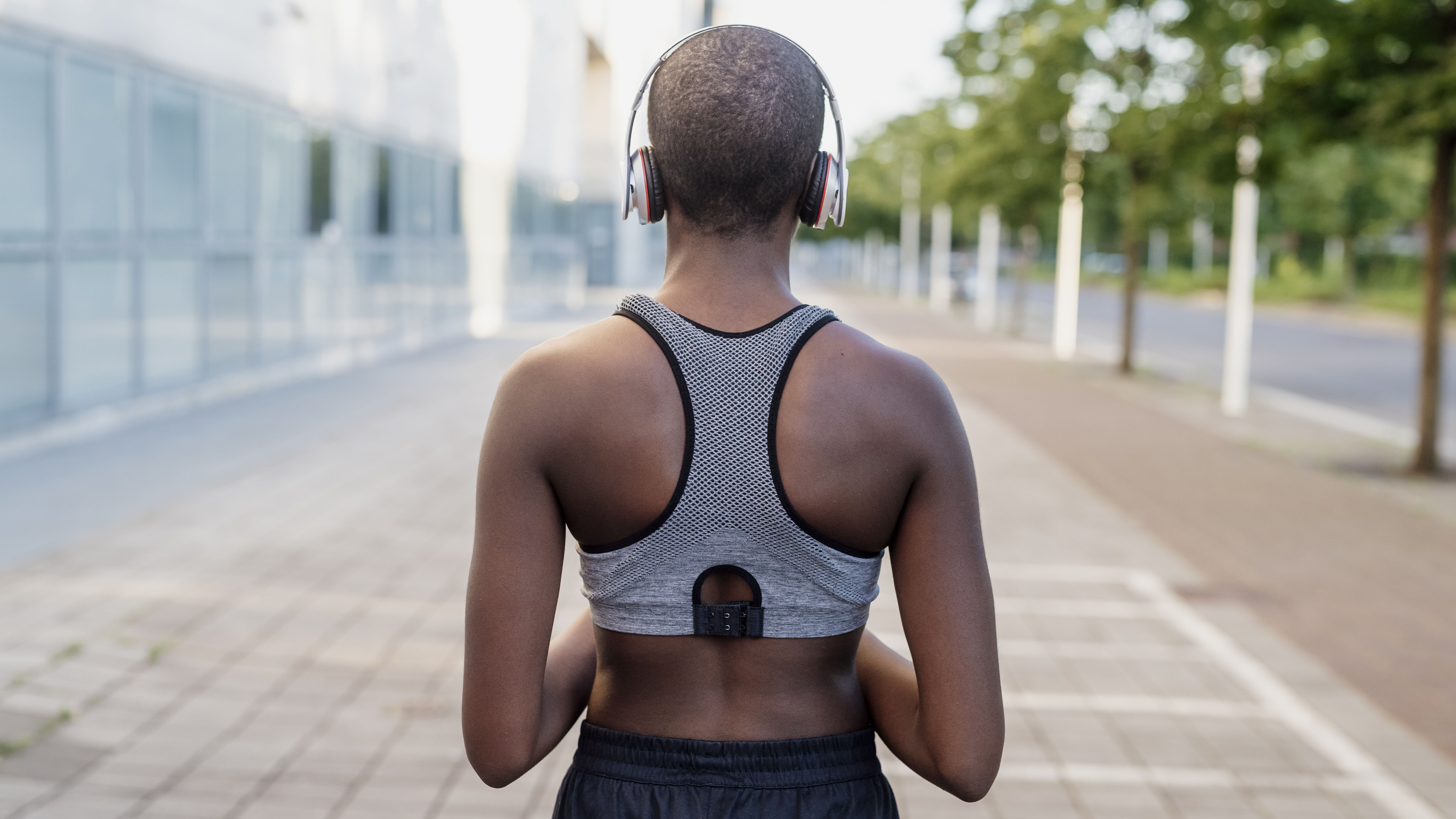 Femme qui court en soutien-gorge de sport en écoutant de la musique avec des écouteurs