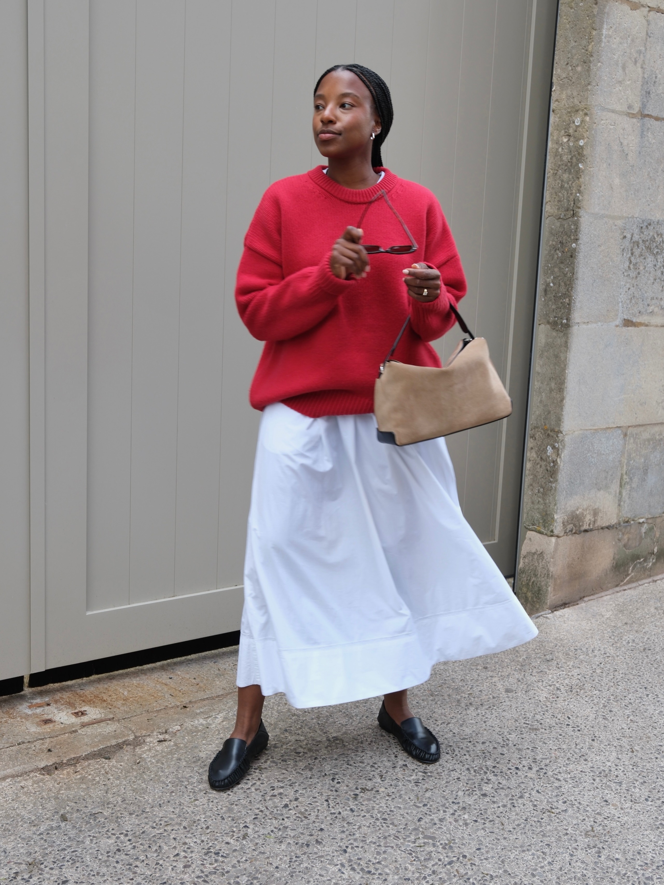 French woman wearing a white maxi skirt, red sweater and black loafers.
