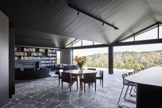 View from inside an Australian house, with stone floor and pitched roofs, looking out to nature