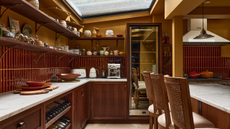 Kitchen with dark maroon tiles and orange walls, a sky light roof and white counters