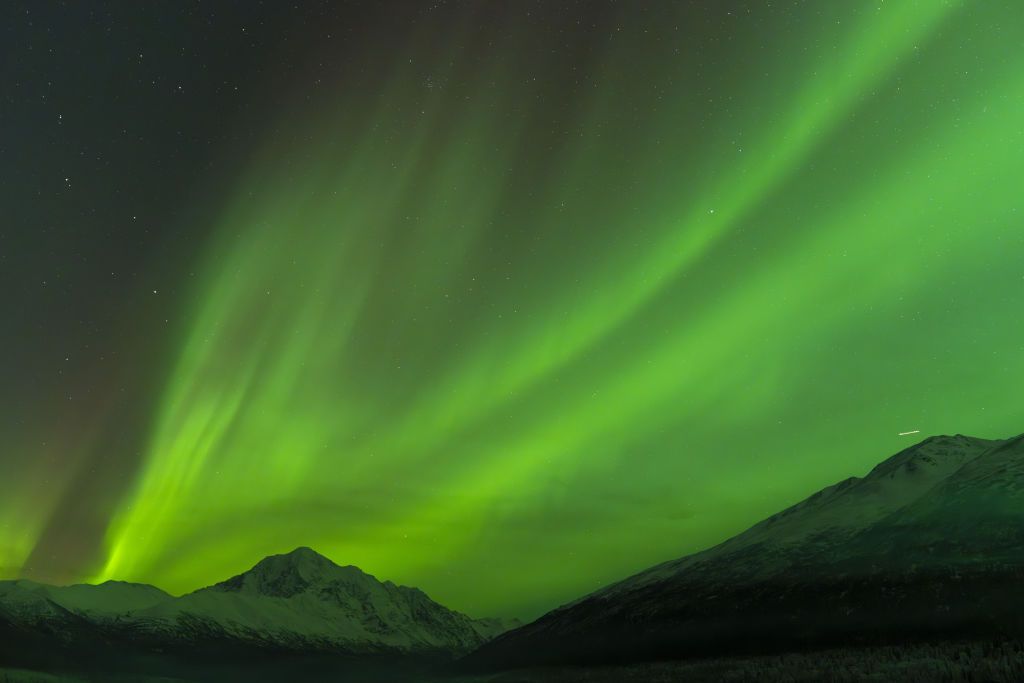 northern lights above alaska during new year's celebrations. large ribbons of green light dance through the sky.