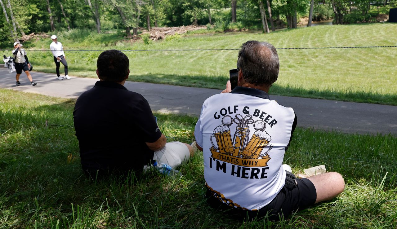 A golfer wears a &#039;golf and beer, that&#039;s why I&#039;m here&#039; t-shirt whilst watching the golf