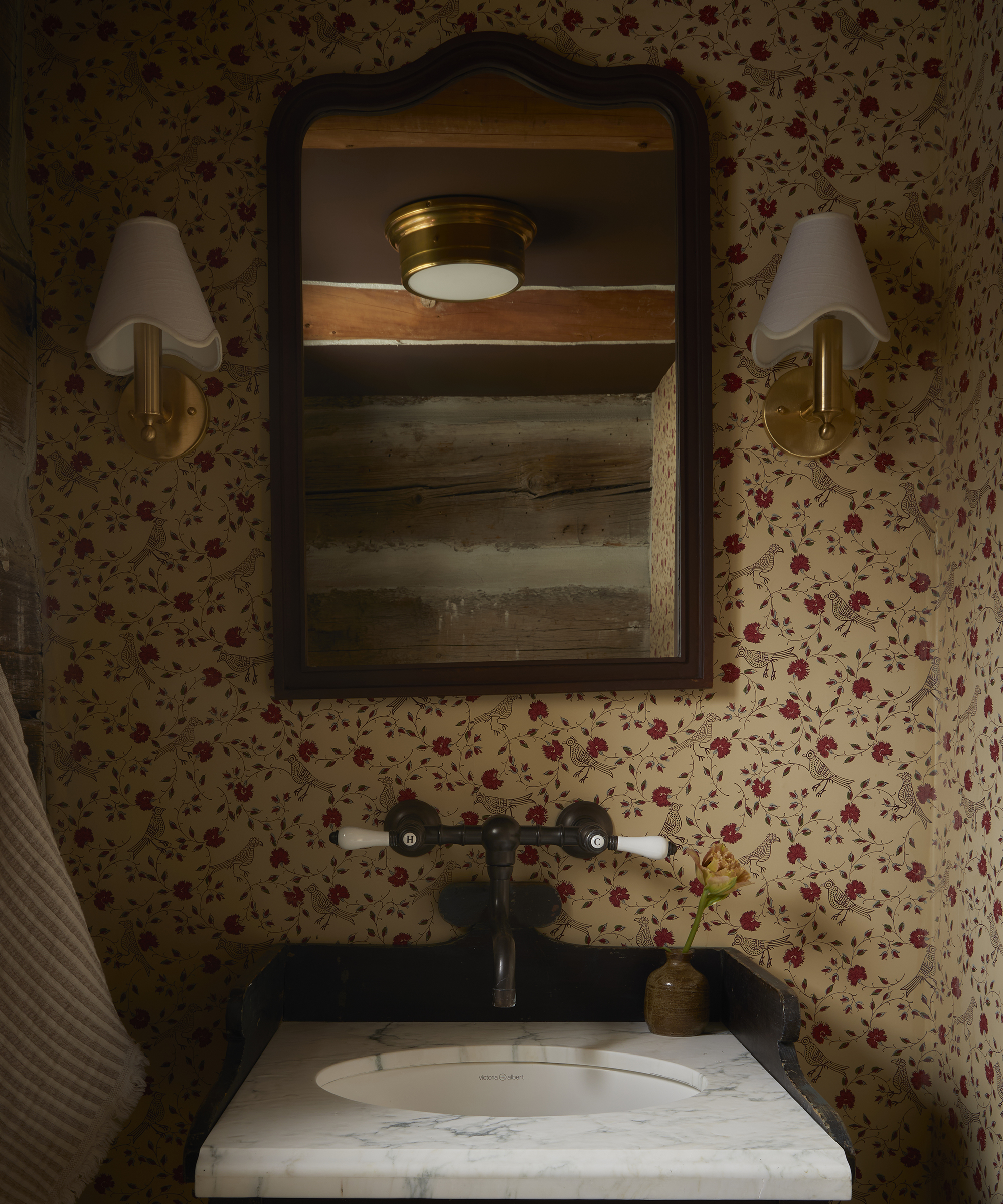 powder room with floral wallpaper and vintage wall lamps on the wall with a vintage mirror