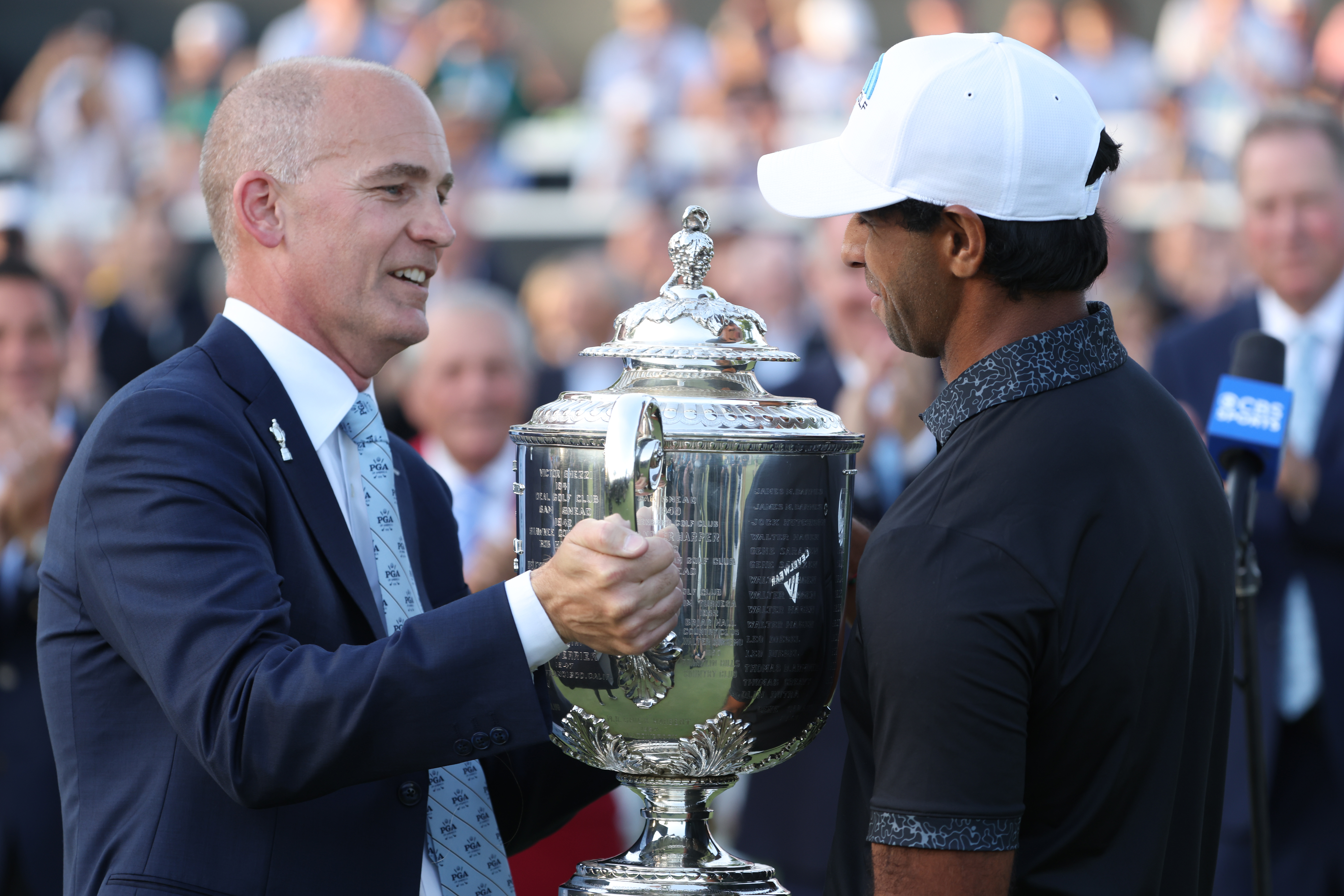 Aaron Rai is presented with The Wanamaker Trophy by PGA of America Vice President Nathan Charnes after winning the 2026 PGA Championship at Aronimink Golf Club