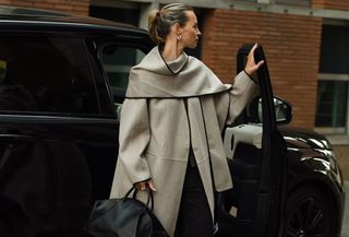 Woman getting out of a car wearing a long scarf coat.