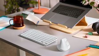 Logitech Lift på et skrivebord med computer, hovedtelefoner og tastatur